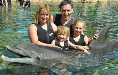 Sam and his family swimming with dolphins